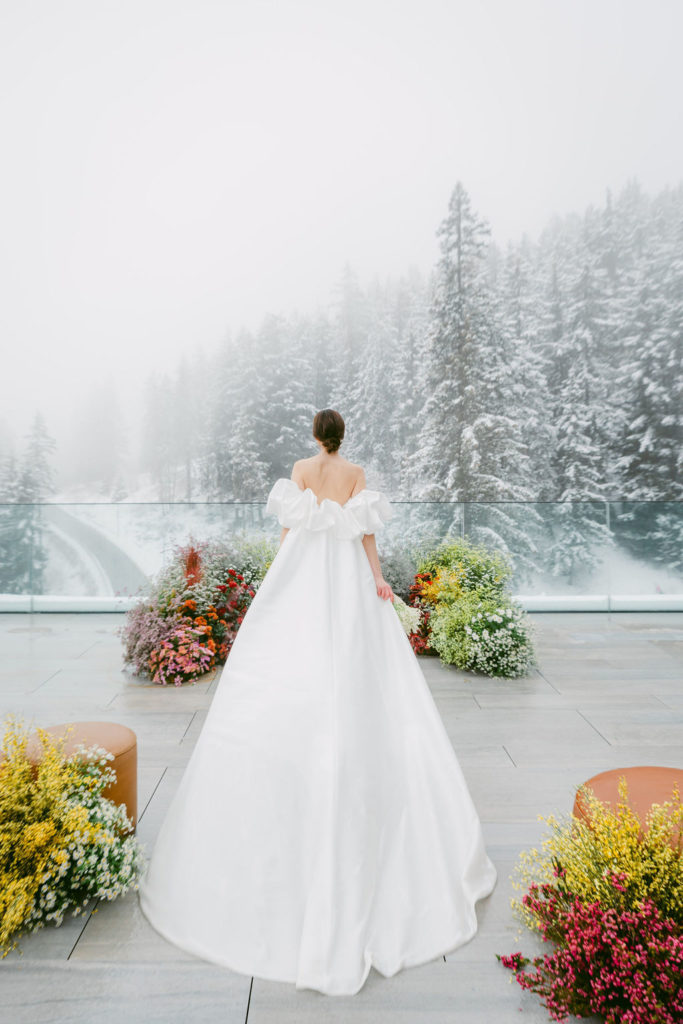 Mariée en robe de mariée satin structurée avec manches sculpturales, shooting hivernal de luxe à Six Senses Crans-Montana